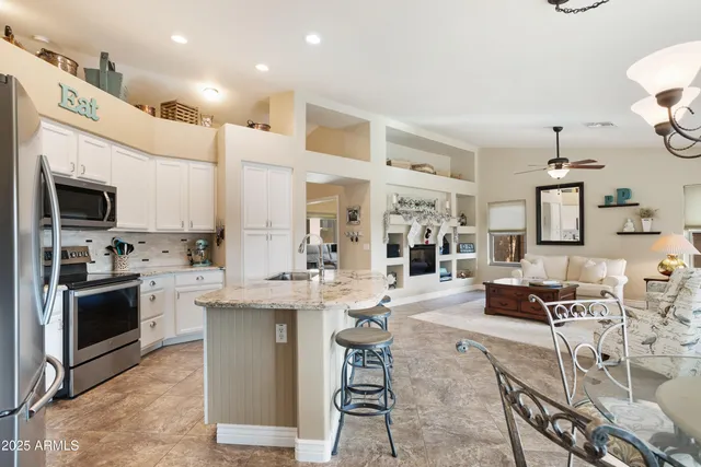 a kitchen with stainless steel appliances kitchen island granite countertop a dining table and chairs