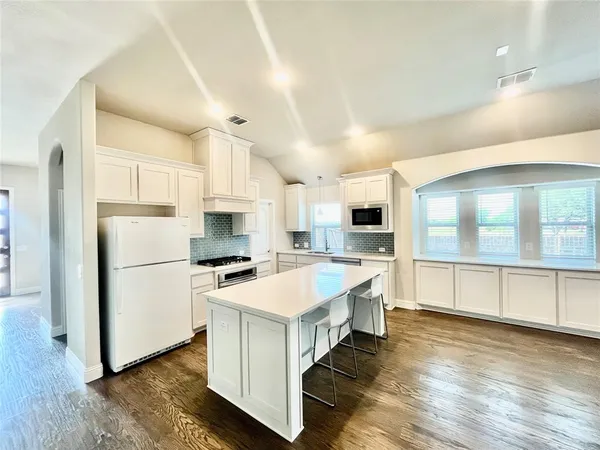 a large white kitchen with lots of counter top space and stainless steel appliances