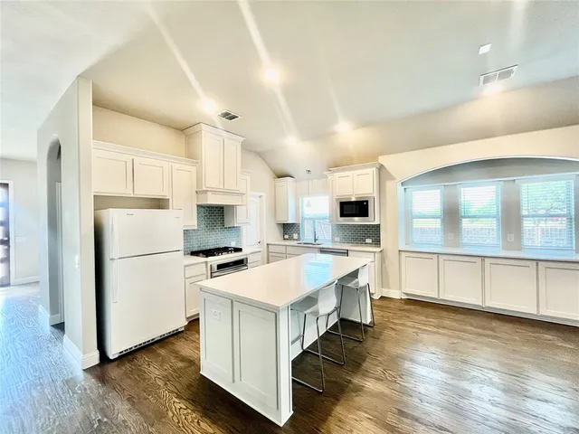 a large white kitchen with lots of counter top space and stainless steel appliances