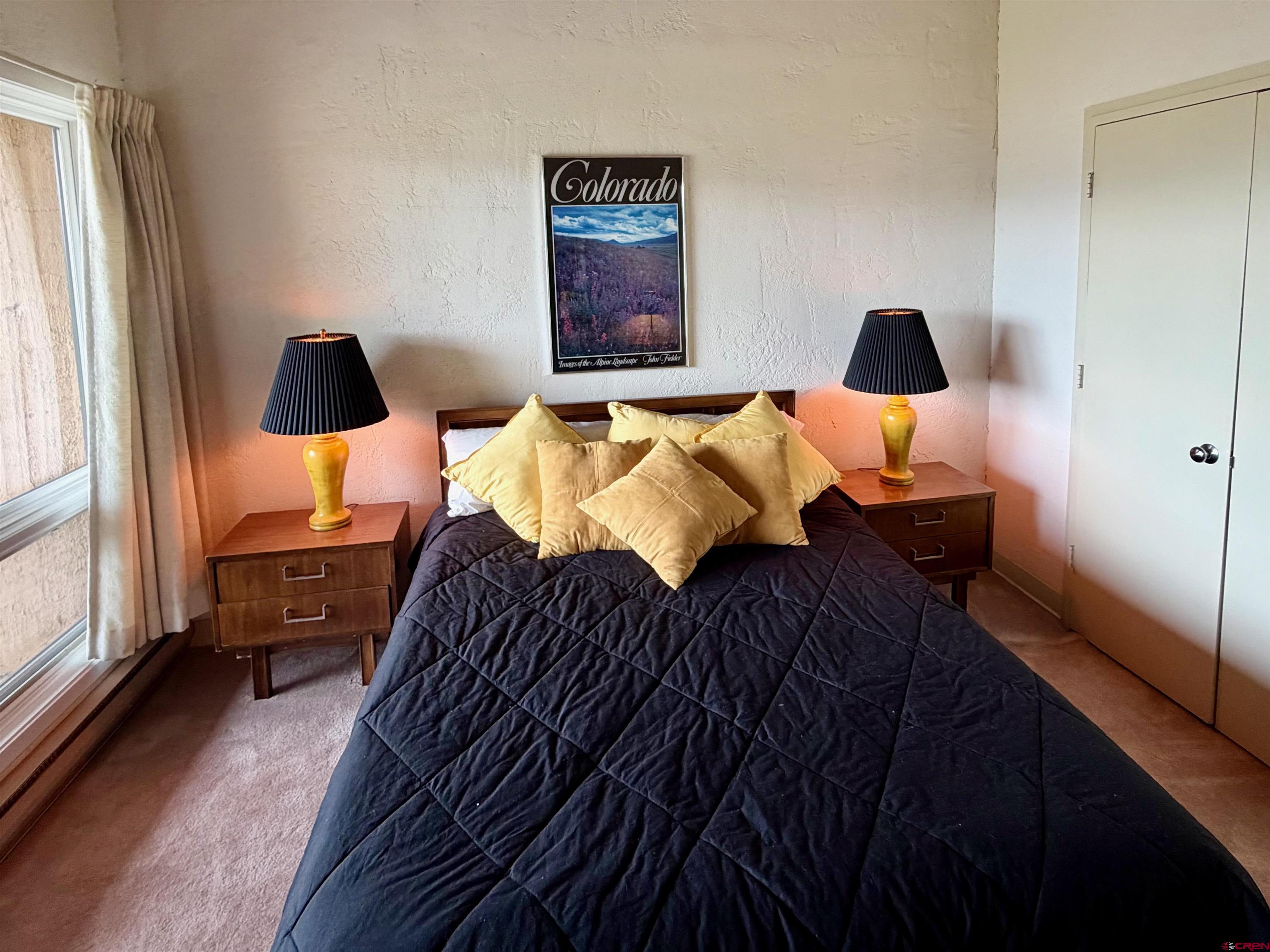51 Whetstone Road, Unit 2306 Crested Butte, CO 81225 - Photo 25 of 44 a bedroom with a bed and a lamp on dresser with wooden floor