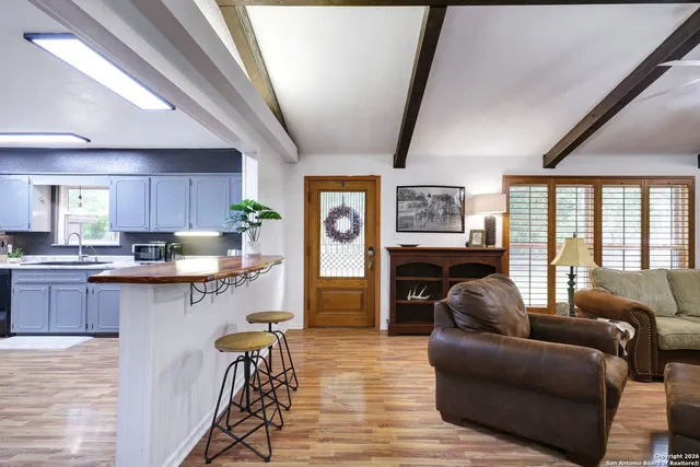 a living room with stainless steel appliances granite countertop furniture a couch a large window and a chandelier