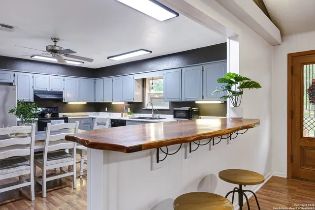 a kitchen with stainless steel appliances kitchen island a table chairs in it and wooden floors