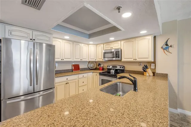 a kitchen with granite countertop a refrigerator a sink a stove a microwave a counter top space and cabinets