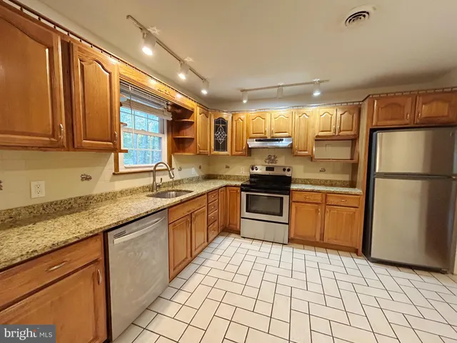 a kitchen with stainless steel appliances granite countertop a refrigerator and a sink