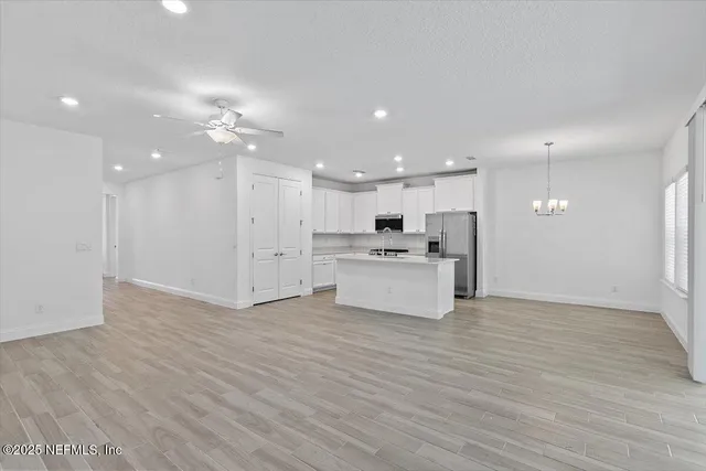 a view of kitchen with kitchen island a sink wooden floor and a refrigerator