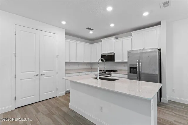 a kitchen with stainless steel appliances a refrigerator sink and microwave
