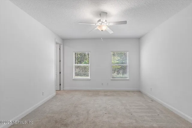 en empty room with windows and chandelier fan