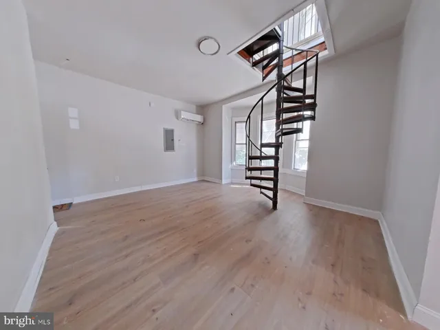 a view of an empty room with stairs and wooden floor