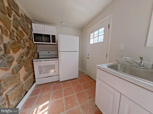 a kitchen with stainless steel appliances a sink a stove a refrigerator a window