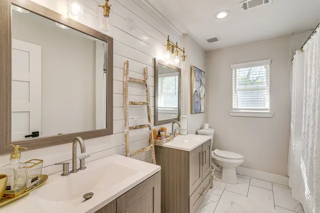 a bathroom with a double vanity sink toilet and a mirror