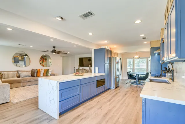 a large kitchen with kitchen island a large counter top space a sink a window and stainless steel appliances