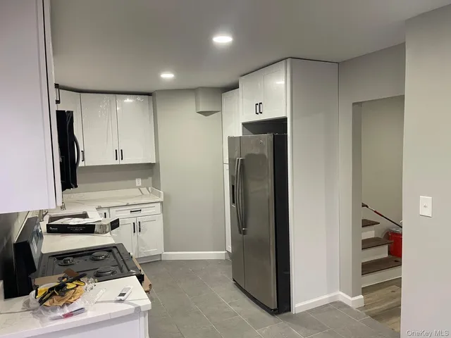a kitchen with a refrigerator and white cabinets