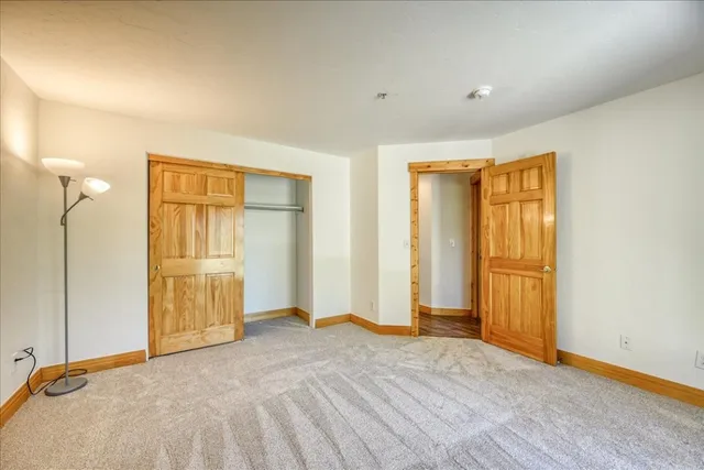 a view of empty room with wooden floor and bathroom