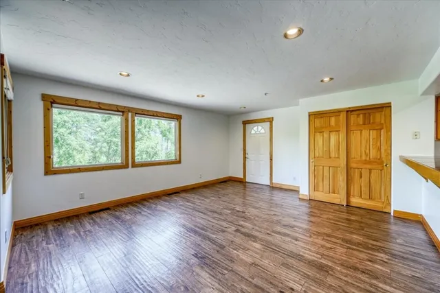 an empty room with wooden floor and windows