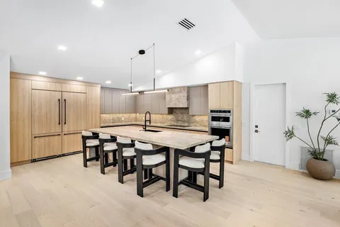 an open kitchen with kitchen island a stove a sink a center island and couches with wooden floor