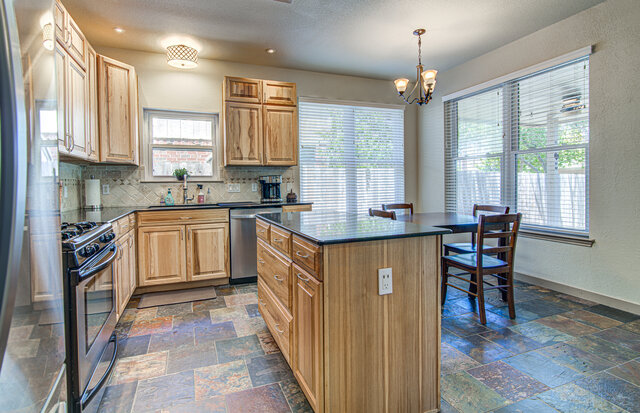 7712 Earp Way Austin, TX 78729 - Photo 7 of 37 a kitchen with stainless steel appliances granite countertop a stove top oven a sink dishwasher a dining table and chairs with wooden floor