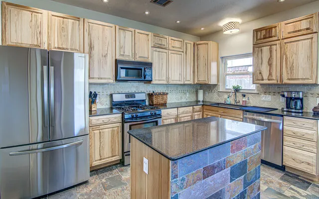 a kitchen with kitchen island granite countertop a sink stainless steel appliances and cabinets