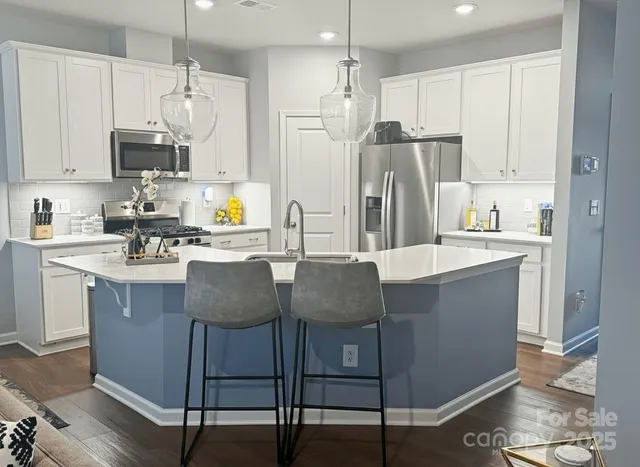 a kitchen with stainless steel appliances granite countertop a table chairs refrigerator and sink