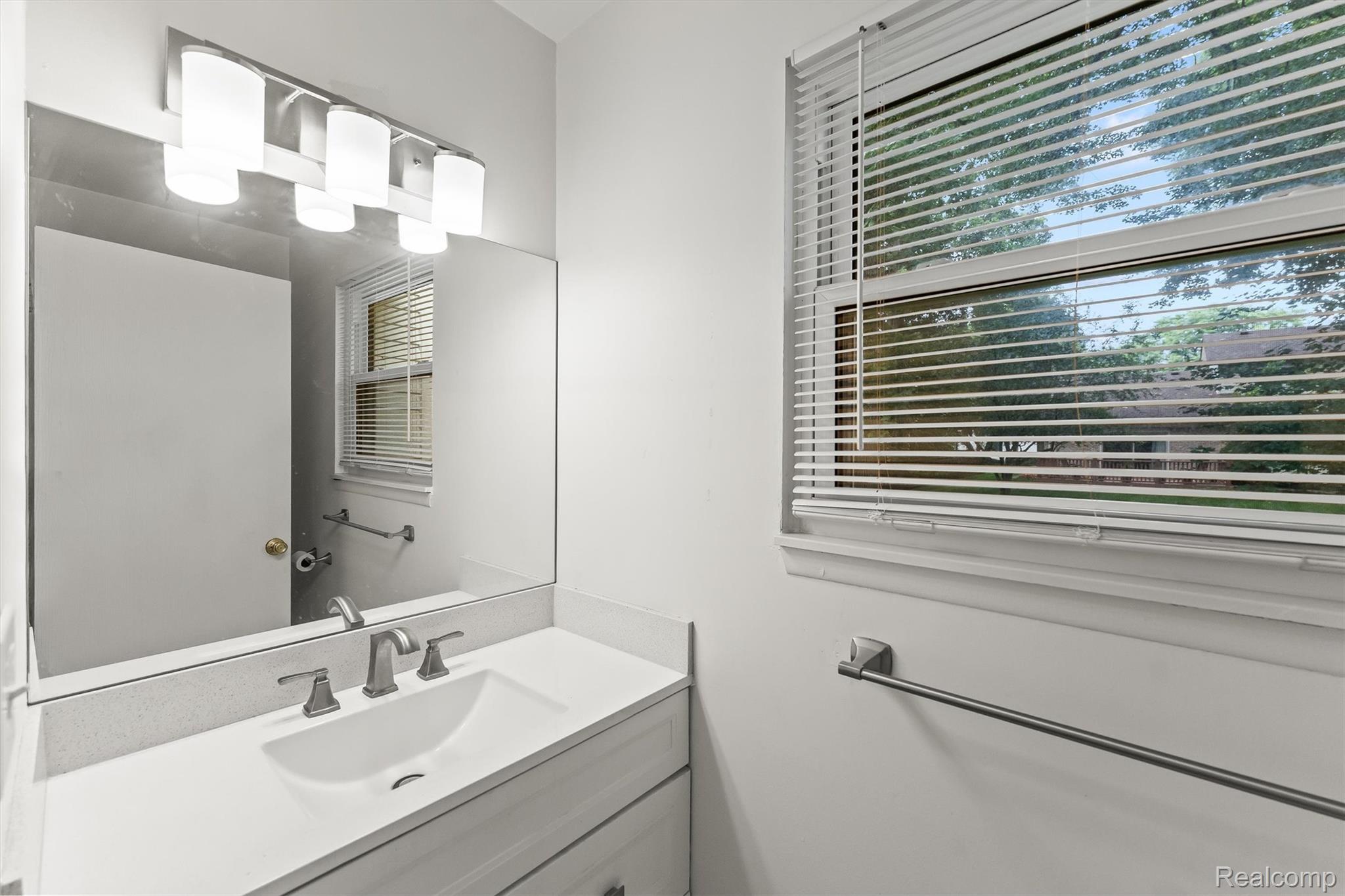 2118 Rutgers Drive Troy, MI 48085 - Photo 31 of 39 Vanity featuring a white countertop with integrated sink, brushed nickel faucet, large mirror, and contemporary light fixture