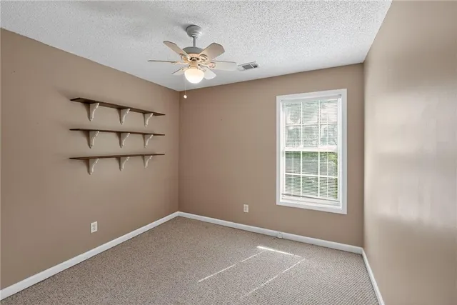 an empty room with windows and fan