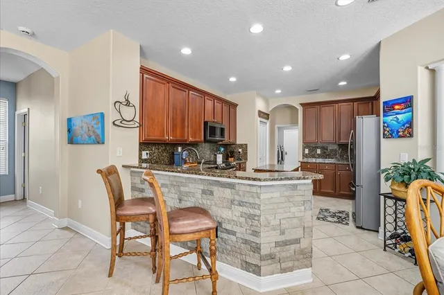 a kitchen with stainless steel appliances kitchen island granite countertop a refrigerator and a stove top oven