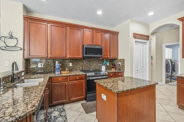 a kitchen with stainless steel appliances granite countertop a stove a sink and a microwave