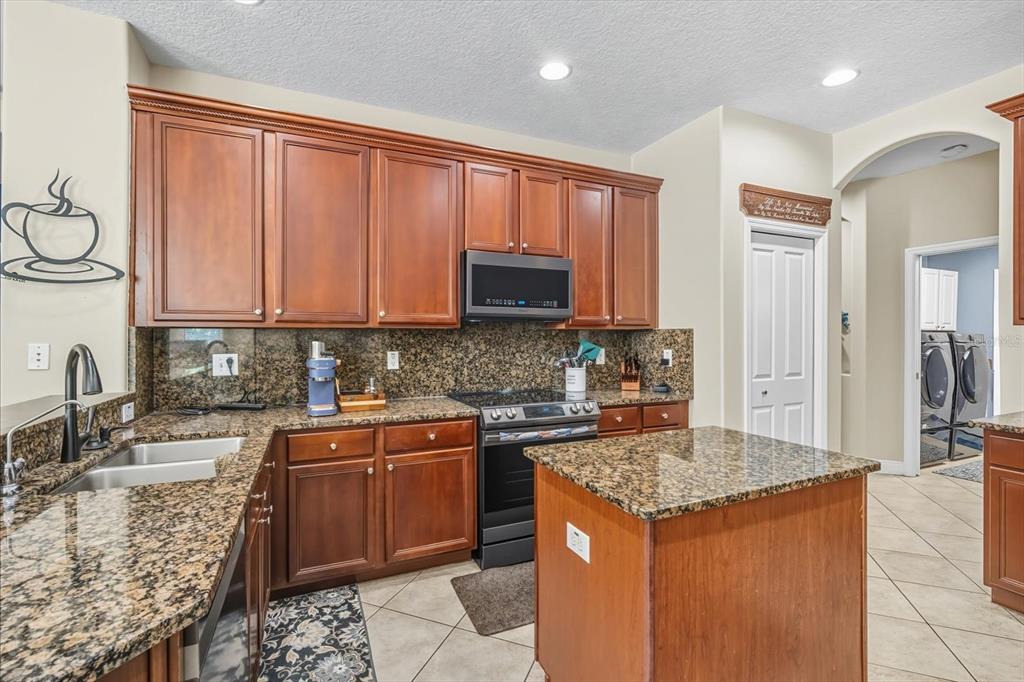 6107 Ibispark Drive Lithia, FL 33547 - Photo 10 of 42 a kitchen with stainless steel appliances granite countertop a stove a sink and a microwave