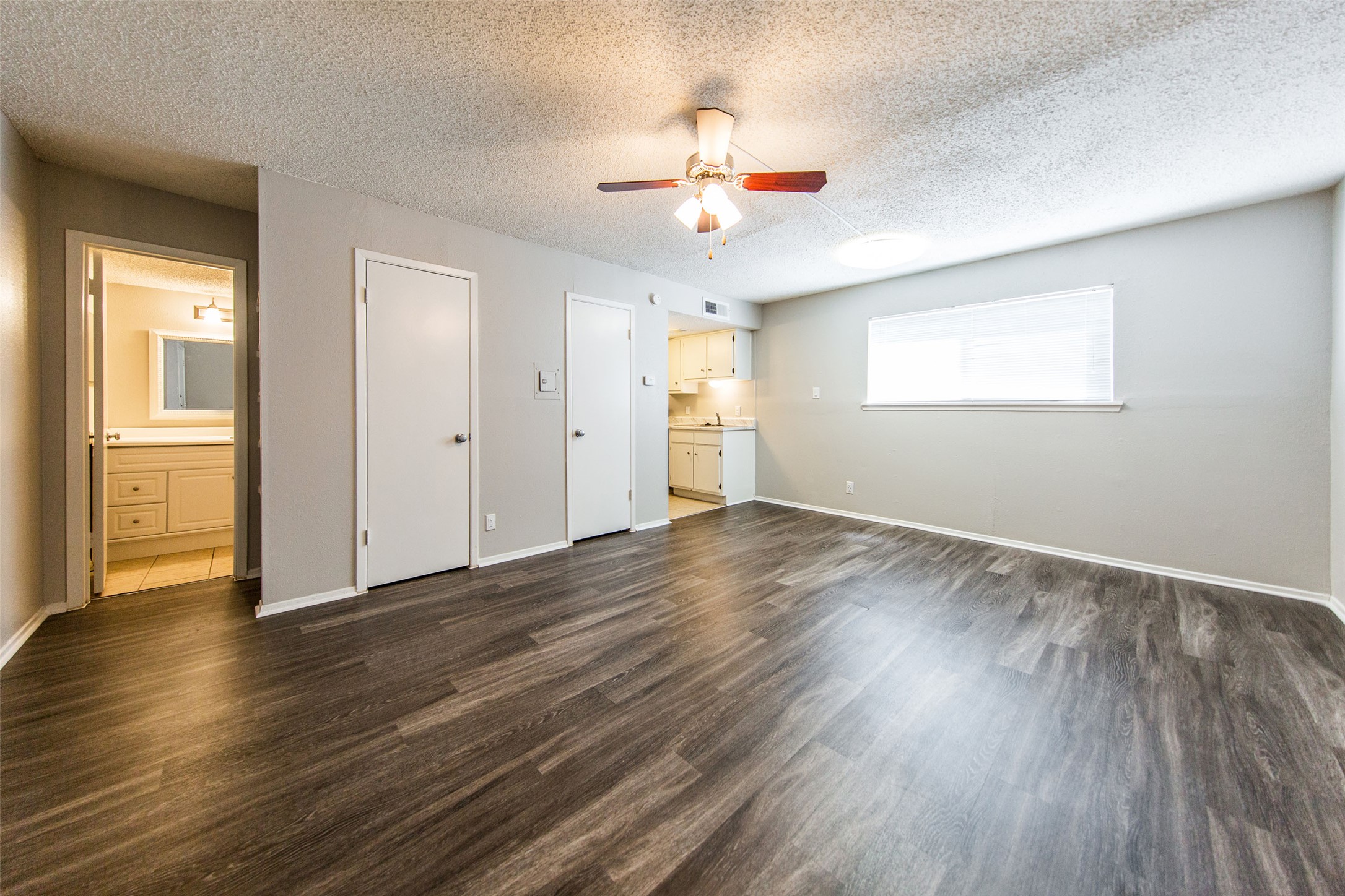 108 West 45th Street, Unit 307 Austin, TX 78751 - Photo 3 of 7 Unfurnished bedroom with ensuite bath, a textured ceiling, dark wood-type flooring, a closet, and ceiling fan