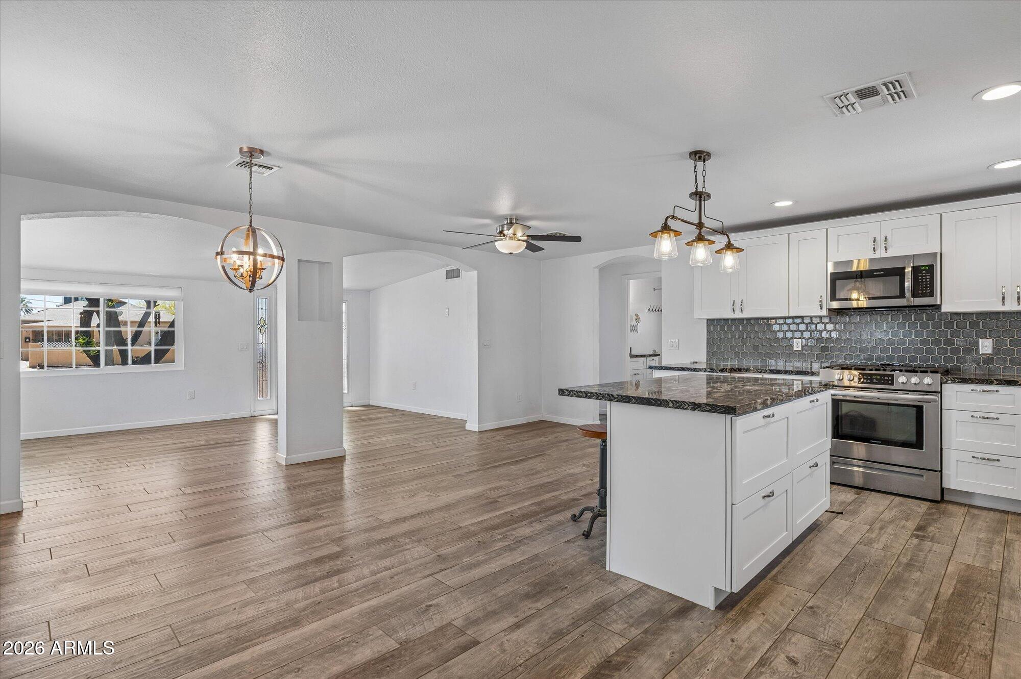 2218 East Yale Street Phoenix, AZ 85006 - Photo 16 of 35 a large kitchen with granite countertop a stove top oven a sink dishwasher a dining table and chairs with wooden floor