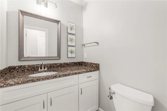 a bathroom with a granite countertop toilet sink and mirror