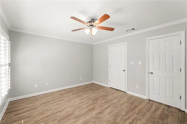 a view of an empty room with window and wooden floor