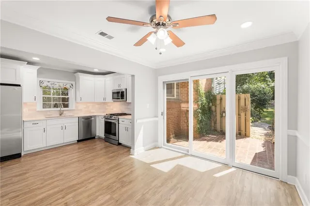 a large kitchen with kitchen island a large window appliances and cabinets