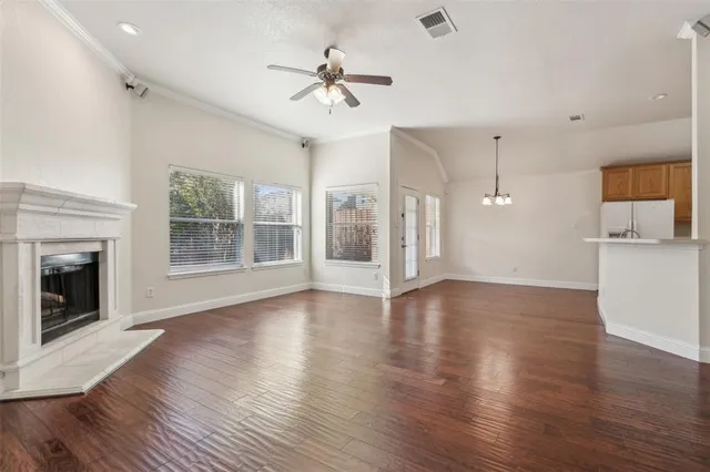 an empty room with wooden floor fireplace and windows