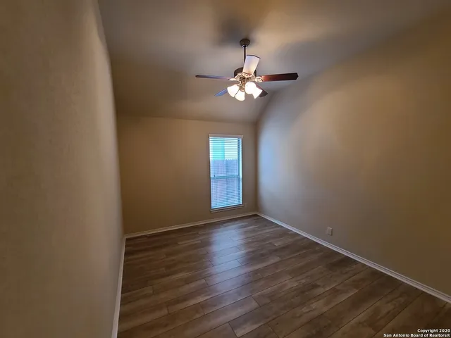 a view of empty room with wooden floor and fan