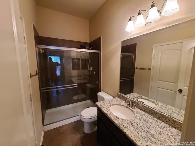 a bathroom with a granite countertop sink toilet and shower