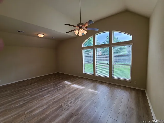 a view of an empty room with wooden floor and a window