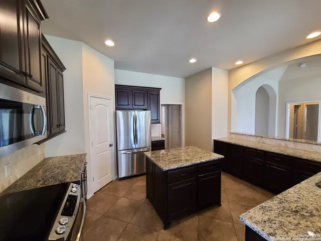 a large kitchen with stainless steel appliances granite countertop a sink stove and refrigerator