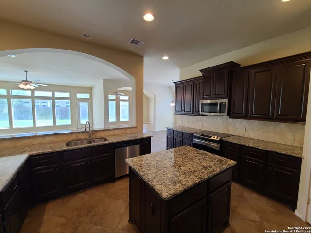 a kitchen with stainless steel appliances granite countertop wooden cabinets a sink and a stove