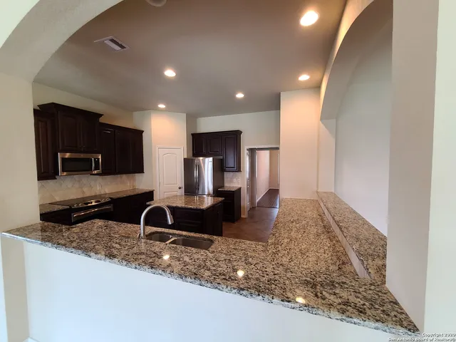 a large kitchen with granite countertop a sink and a stove top oven