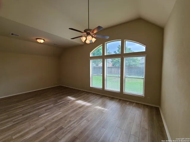 a view of an empty room with a window and wooden floor