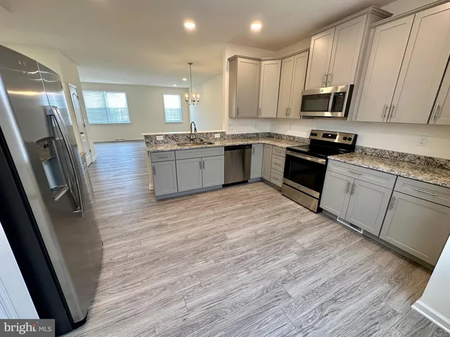 a large kitchen with stainless steel appliances granite countertop a stove a sink dishwasher and a refrigerator