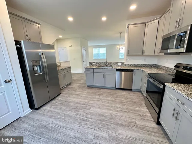 a large kitchen with stainless steel appliances granite countertop a stove a sink dishwasher a refrigerator and a oven with wooden floor