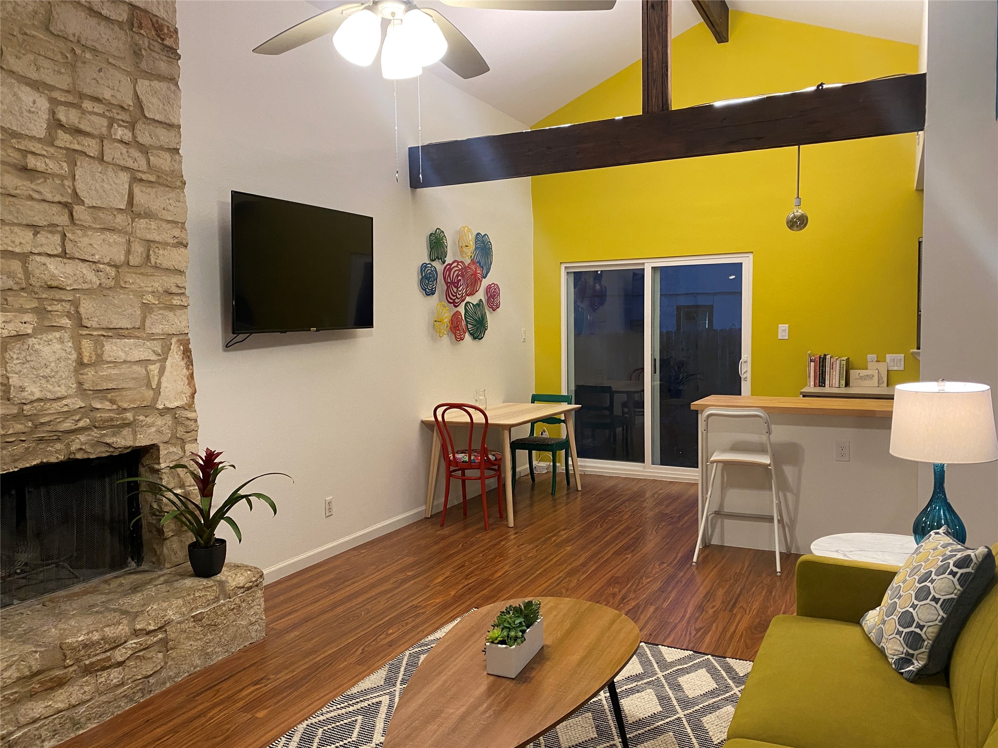 5405 Brompton Circle, Unit B Austin, TX 78745 - Photo 5 of 19 Living area featuring ceiling fan, wood finished floors, a stone fireplace, beam ceiling, and high vaulted ceiling