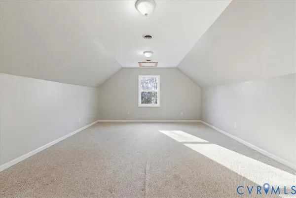 an empty room with a chandelier fan and windows