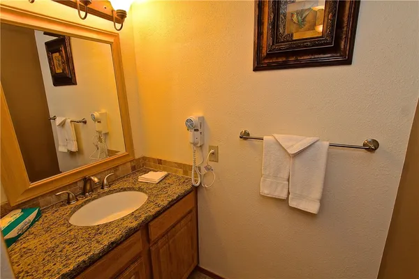 a bathroom with a granite countertop double vanity sink and mirror
