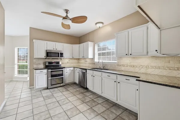 a kitchen with granite countertop a stove a sink and a refrigerator