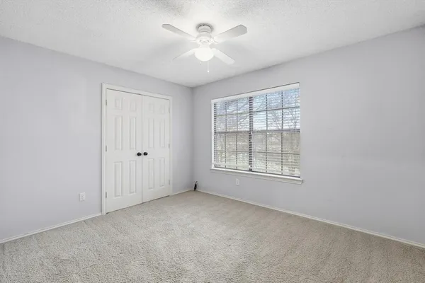 an empty room with windows and ceiling fan