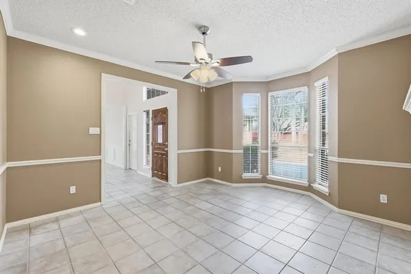 an empty room with chandelier fan and windows
