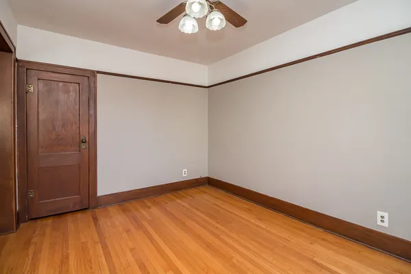 an empty room with a hardwood and ceiling fan
