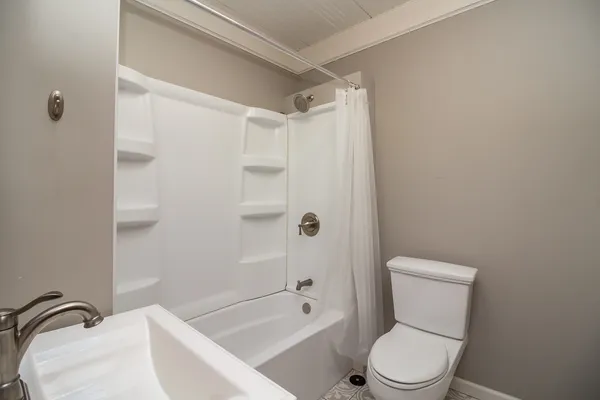 a white toilet sitting next to a bath tub